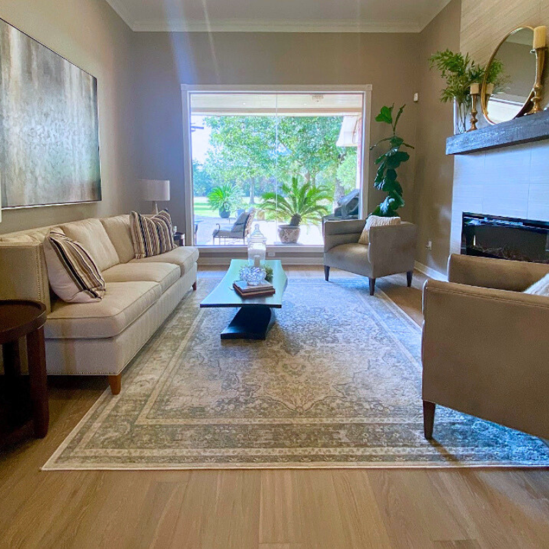 Light oak hardwood flooring installed in a modern living room with natural light and a large patterned rug.