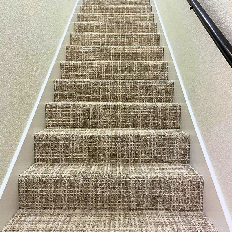 Plaid patterned carpet expertly installed on a staircase.