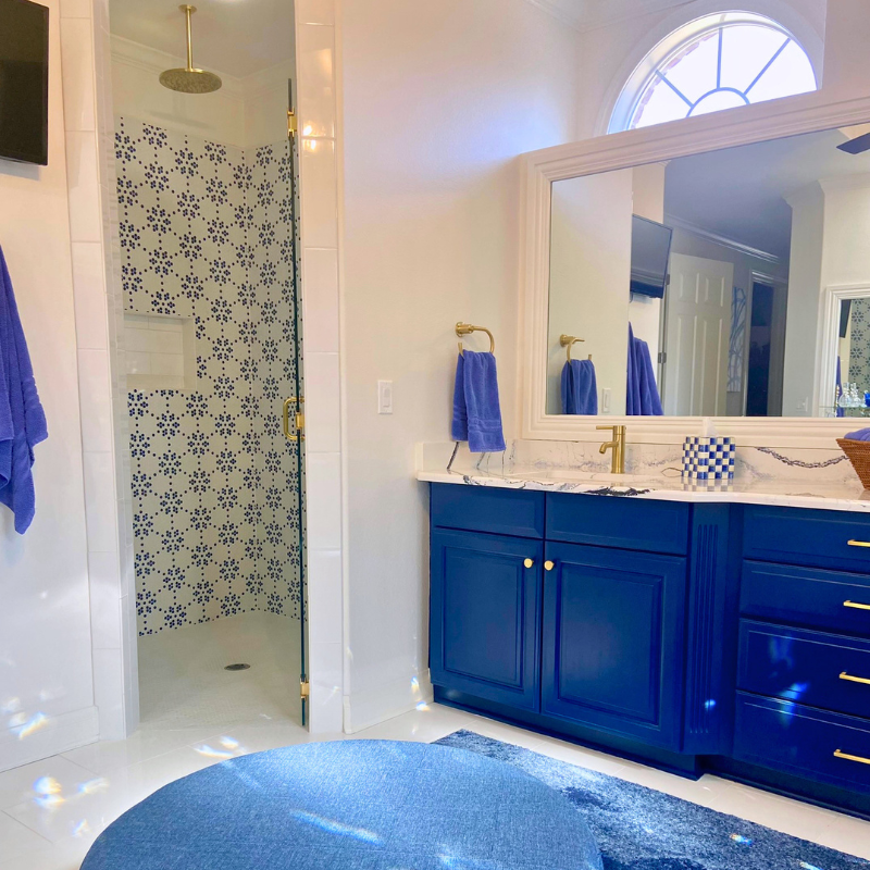 Dainty blue and white tile mosaic in the shower and glossy white tile installed in a master bathroom.