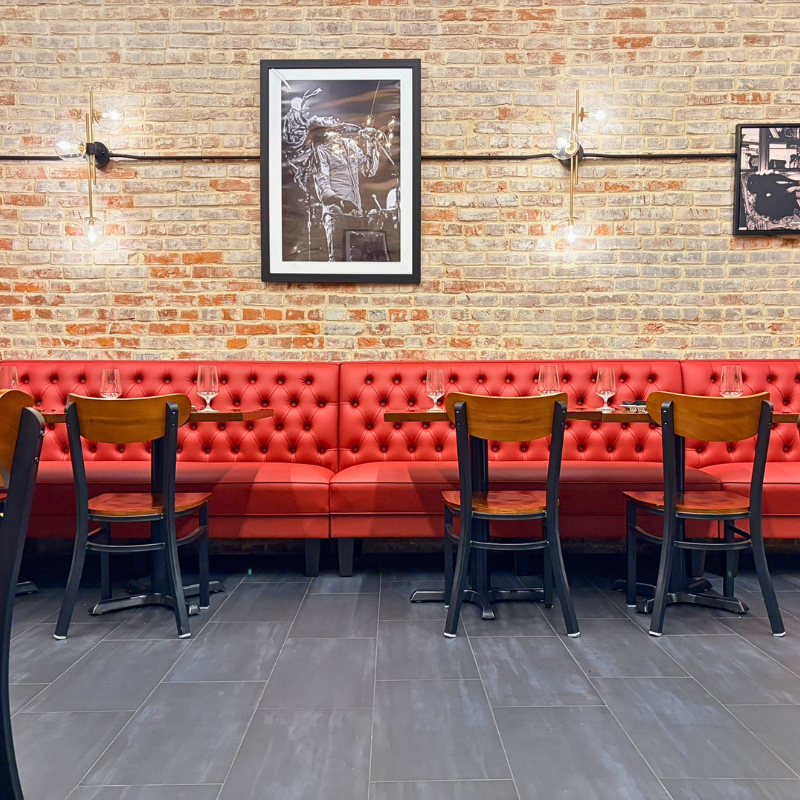 Gray, commercial-grade tile in a local restaurant with an exposed brick wall, red tufted booth and vintage wall art.