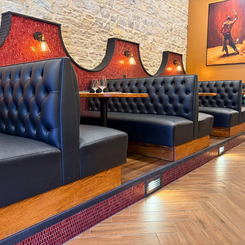 Herringbone wood-look tile with red backsplash tile in a local restaurant with tufted black booths.